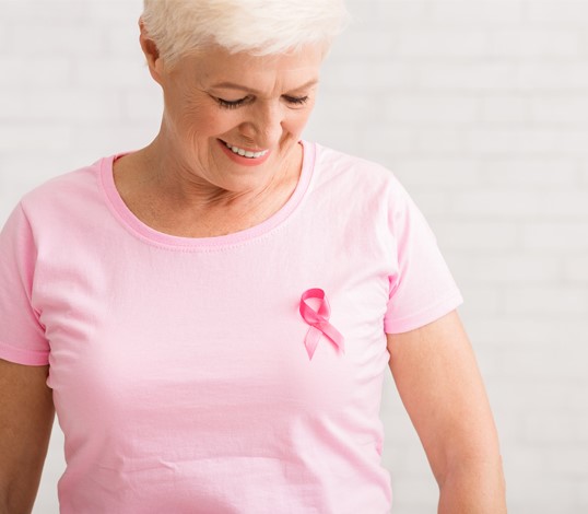 Older woman wearing pink t-shirt with cancer ribbon attached