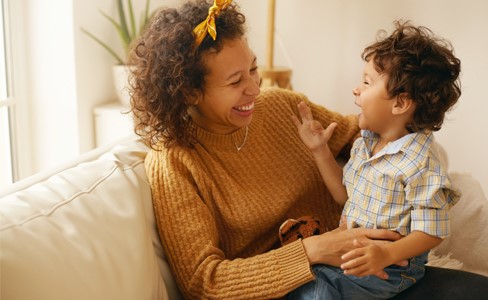 Mother and infant son gleefully laughing on a couch