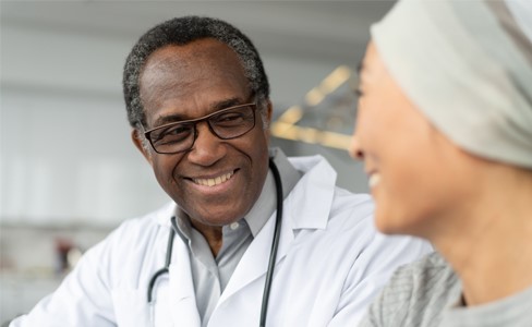 In-focus doctor laughing about something with a blurry patient in a kitchen